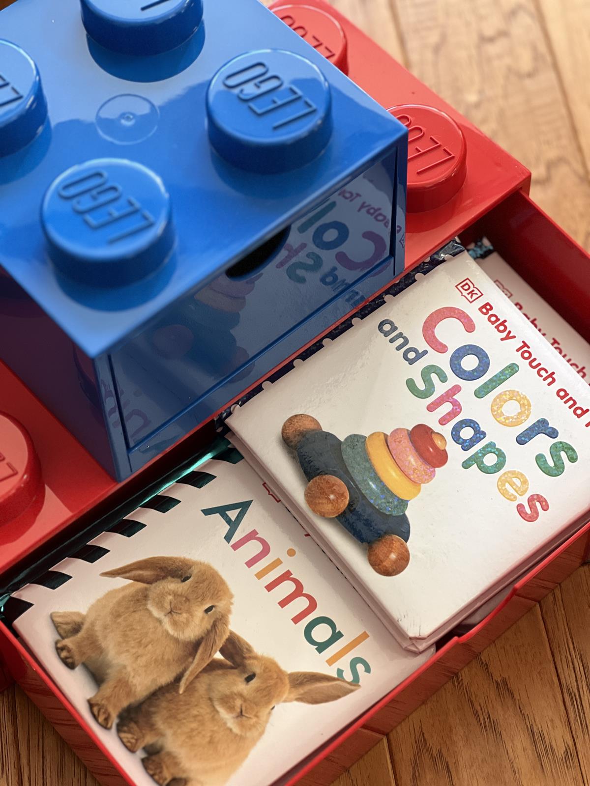 baby books in a red and blue Lego storage boxes